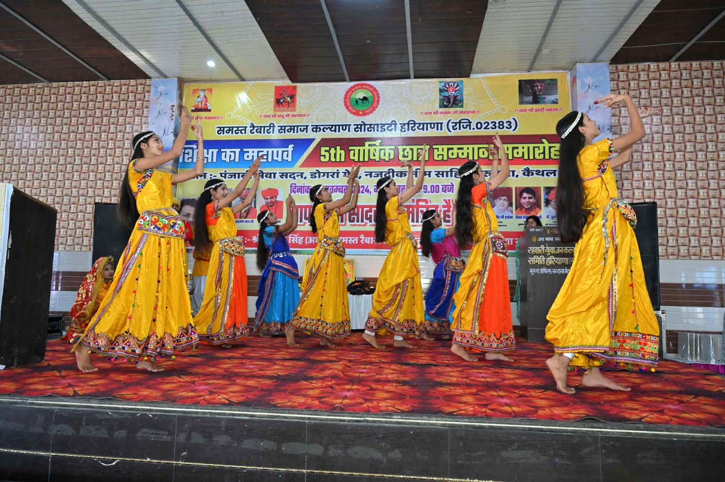 Young performers in yellow and orange traditional dresses dancing together on stage